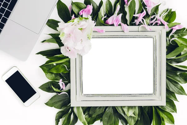 Wooden frame decorated with flowers and leaves, laptop and phone. empty space for text — Stock Photo, Image