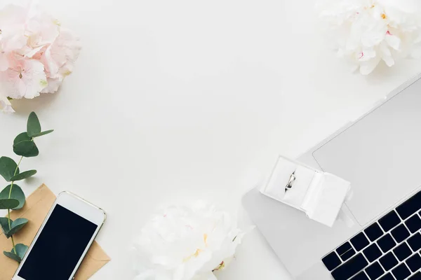 花と携帯電話の背景に白いギフト ボックスの結婚指輪。トップ ビュー — ストック写真
