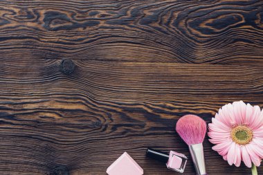 Pembe gerbera, makyaj fırça, tırnak cilası ahşap arka plan, üstten görünüm üzerinde. Metin için yer