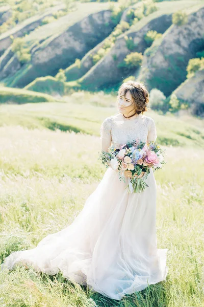 Bellas artes fotografía de boda. Hermosa novia con ramo y vestido con tren en la naturaleza — Foto de Stock