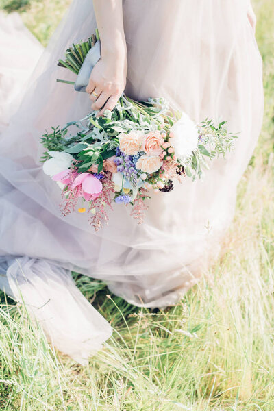 Brides hands hold a beautiful bridal bouquet of peony. fine art photography.