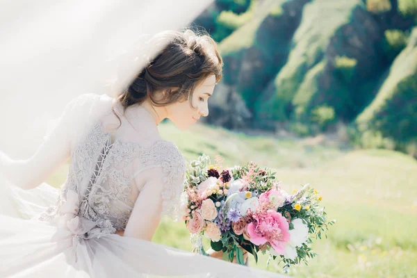 Bellas artes fotografía de boda. Hermosa novia con ramo y vestido con tren en la naturaleza — Foto de Stock