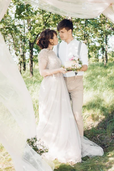 Pareja de boda en la naturaleza. la novia y el novio con la torta a la boda . —  Fotos de Stock