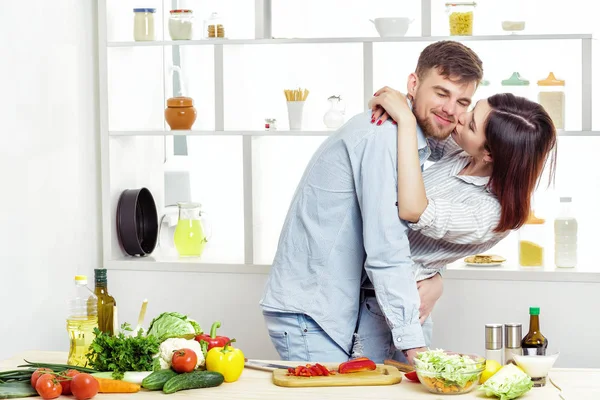 爱幸福的夫妇准备健康新鲜的蔬菜沙拉在厨房里。情侣接吻 — 图库照片