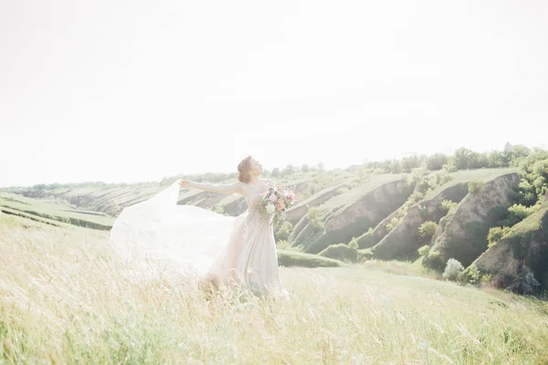 Fotografia de casamento de arte. Bela noiva com buquê e vestido com trem na natureza — Fotografia de Stock