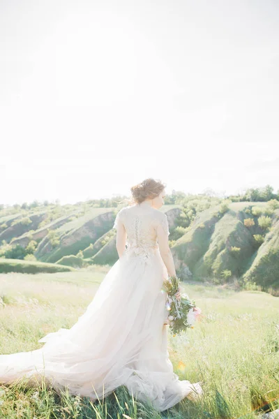 fine art wedding photography. Beautiful bride with bouquet and dress with train in nature