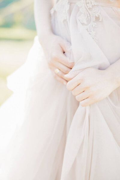 Hands of the bride on a wedding dress on a sunny day. fine art photography.