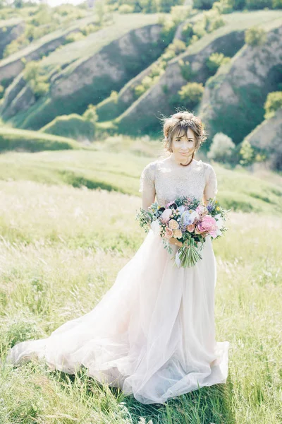 Bellas artes fotografía de boda. Hermosa novia con ramo y vestido con tren en la naturaleza — Foto de Stock