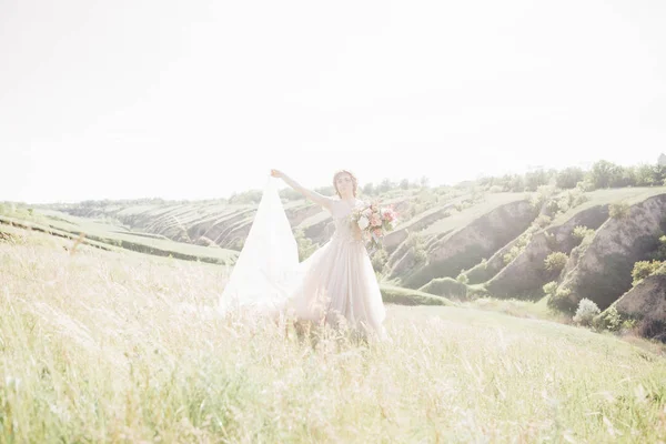 Fotografia de casamento de arte. Bela noiva com buquê e vestido com trem na natureza — Fotografia de Stock