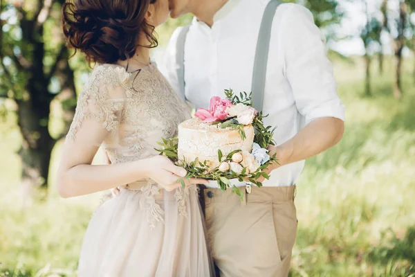 Pareja de boda en la naturaleza. la novia y el novio con la torta a la boda . — Foto de Stock