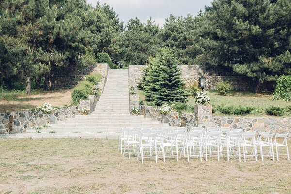 Many rows of white wooden chairs for wedding ceremony in nature