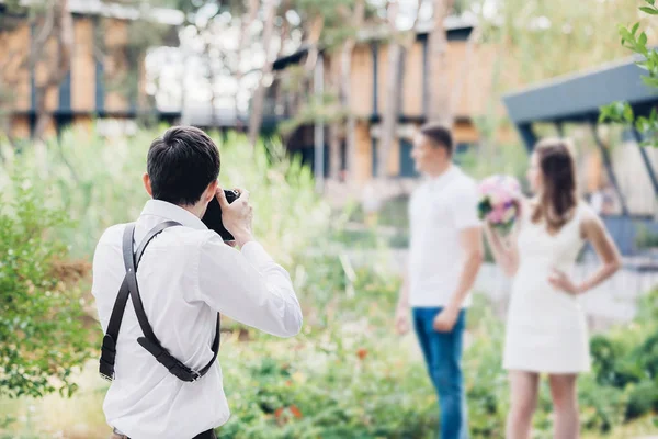 Fotograf ślubny robi zdjęcia para zakochanych w przyrodzie w okresie letnim — Zdjęcie stockowe
