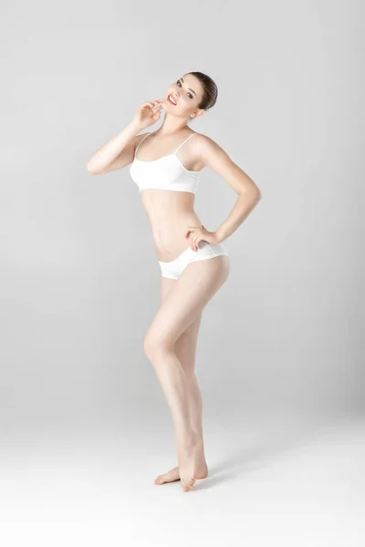 Deportiva hermosa mujer con cuerpo perfecto en lencería blanca sobre fondo gris — Foto de Stock