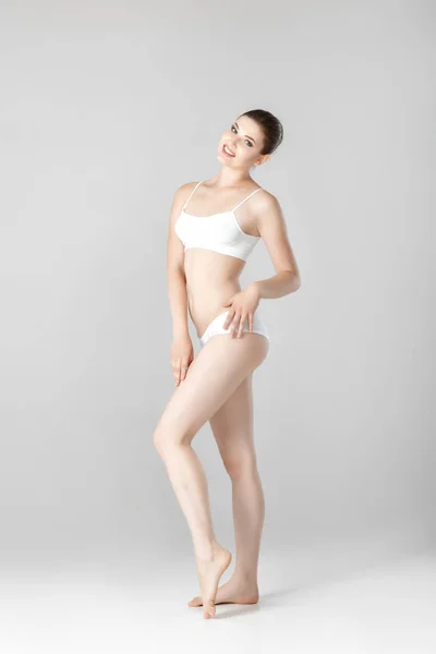 Slanke mooie vrouw met perfect lichaam in witte lingerie op grijze achtergrond — Stockfoto