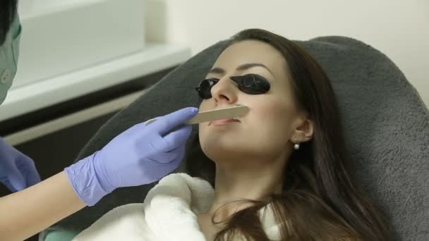 Косметолог наносить гель на обличчя пацієнта перед процедурою епіляції — стокове відео