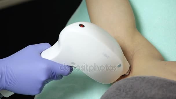 Косметолог проводит лазерную эпиляцию подмышек пациента. Процедура эпиляции — стоковое видео