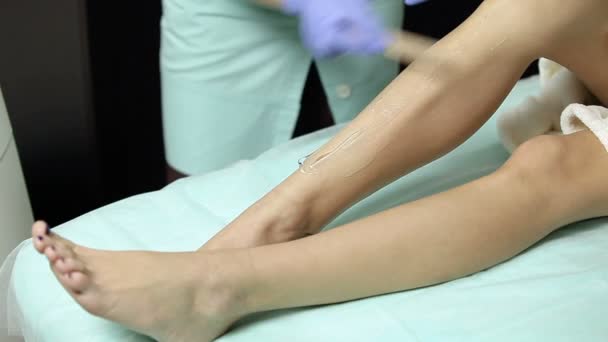 Cosmetólogo aplica gel a los pies de los pacientes antes del procedimiento de depilación — Vídeos de Stock