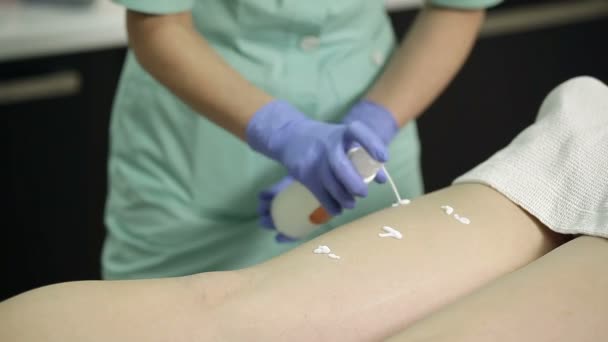 Cosmetólogo aplica crema a los pies de los pacientes después del procedimiento de depilación — Vídeo de stock