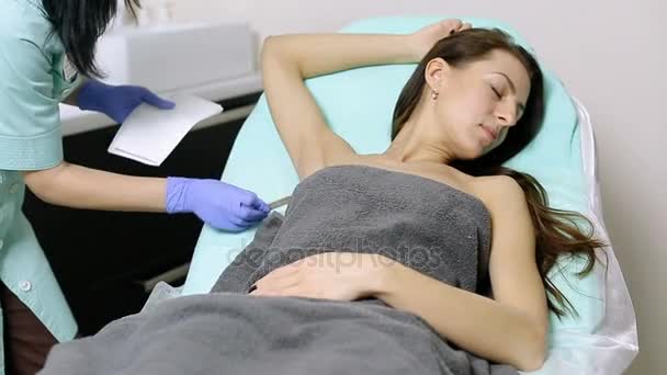 Косметолог наносит гель на подмышки пациента перед процедурой эпиляции — стоковое видео