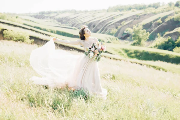 Bellas artes fotografía de boda. Hermosa novia con ramo y vestido con tren en la naturaleza — Foto de Stock