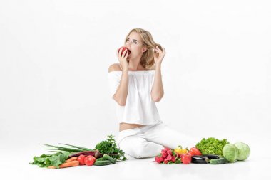 Beyaz elbise ve beyaz arka plan üzerinde taze sebze güzel sarışın kadın. Kız nektarin yiyor