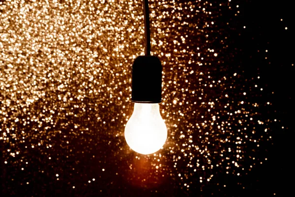 Light bulb on a black background  with sparkles — Stock Photo, Image