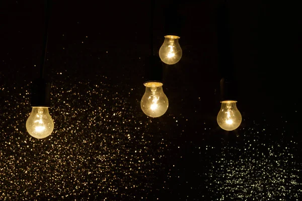 Light bulbs on a black background with sparkles — Stock Photo, Image