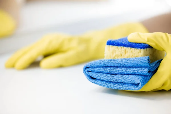 Hand in een rubber gele handschoen holding spons. — Stockfoto