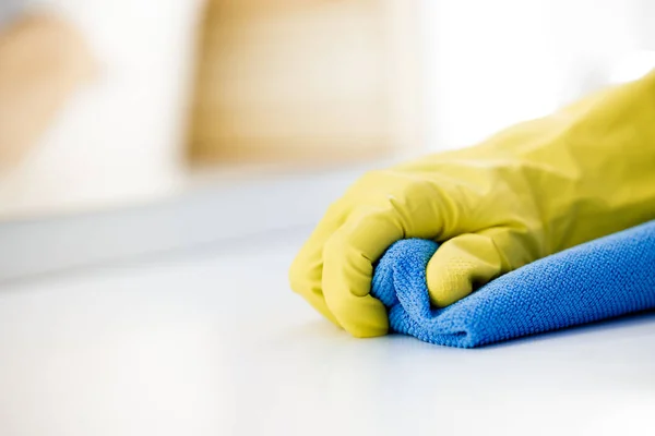 Main féminine en gant caoutchouc jaune nettoie la surface de la table — Photo