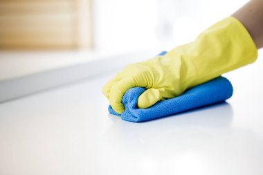 El sarı lastik eldiven içinde tablo yüzeyini temizler