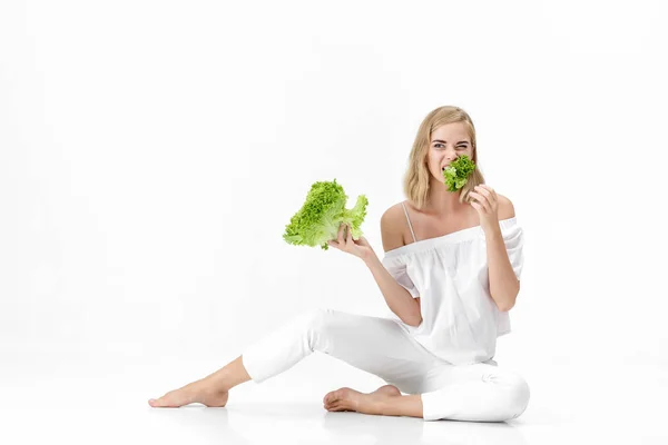 Beautiful blond woman in white blouse eating fresh green salad on white background. Health and Diet — Stock Photo, Image