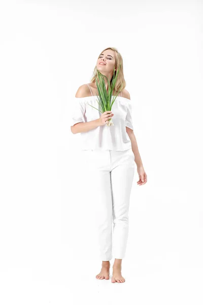 Mulher loira bonita em blusa branca segurando cebola verde no fundo branco. Saúde e vitaminas — Fotografia de Stock