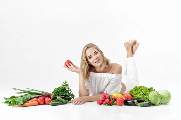 Schöne blonde Frau in weißen Kleidern und viel frisches Gemüse auf weißem Hintergrund — Stockfoto