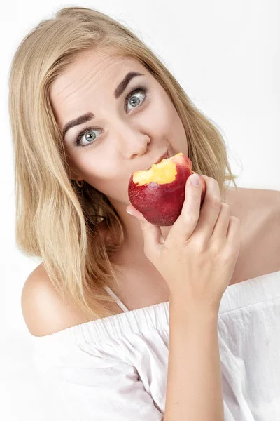Vacker blond kvinna med glädje äter nektarin — Stockfoto