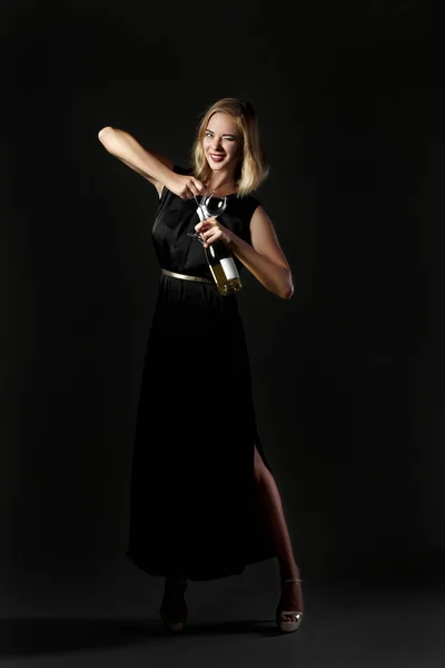 Όμορφη ξανθιά γυναίκα κρατώντας το μπουκάλι λευκό κρασί σε μαύρο φόντο. Διακοπές και πάρτι — Φωτογραφία Αρχείου