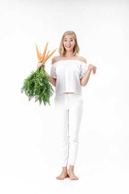 Tavşan gösterilen ve beyaz zemin üzerine yeşil yaprakları ile taze havuç tutan güzel sarışın bir kadın. Sağlık ve diyet