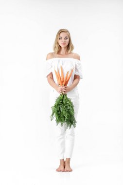 Yeşil taze havuç tutan güzel sarışın kadın beyaz zemin üzerine bırakır. Sağlık ve diyet