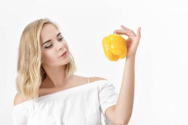 Beyaz bluz sarı dolmalık biber tutan güzel sarışın kadın. Sağlık ve diyet