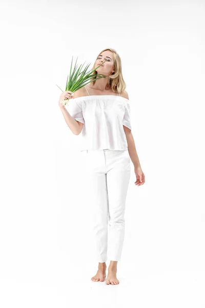 Schöne blonde Frau in weißer Bluse mit grüner Zwiebel auf weißem Hintergrund. Gesundheit und Vitamine — Stockfoto