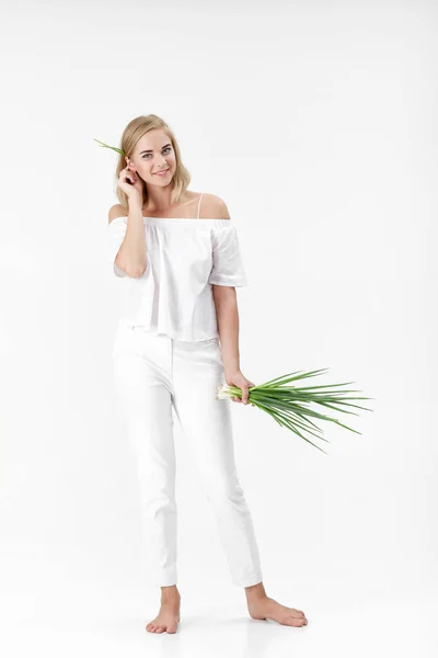 Mooie blonde vrouw in witte blouse bedrijf groene ui op witte achtergrond. Gezondheid en vitaminen — Stockfoto