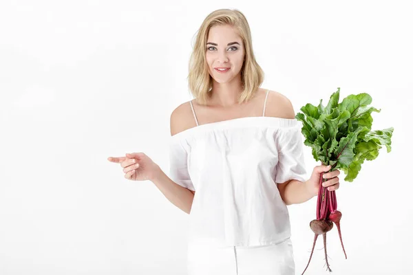 Beautiful blond woman holds beetroot with green leaves on white background. Health and vitamins — Stock Photo, Image