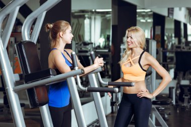Spor salonunda konuşurken iki atletik sarışın kadın. Kız eğitmen ile iletişim