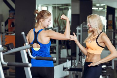 Spor salonunda konuşurken iki atletik sarışın kadın. Kız eğitmen ile iletişim