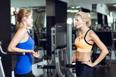 Spor salonunda konuşurken iki atletik sarışın kadın. Kız eğitmen ile iletişim