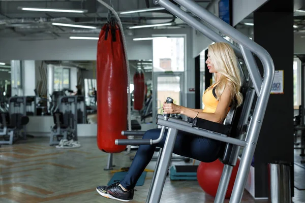 Mujer atlética rubia usando máquina de prensa en el gimnasio —  Fotos de Stock