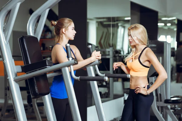 Två atletisk blonda kvinnor talar i gymmet. Flicka kommunicerar med tränare — Stockfoto