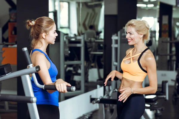 Két sportos szőke nő beszél az edzőteremben. Lány kommunikál, edző — Stock Fotó