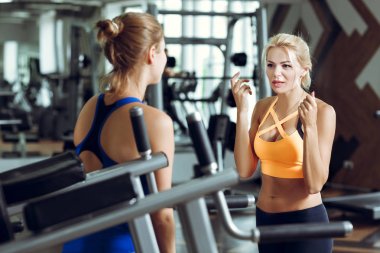 Spor salonunda konuşurken iki atletik sarışın kadın. Kız eğitmen ile iletişim