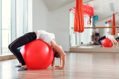 Genç atletik kadın fitness topu içinde jimnastik salonu ile yapıyor
