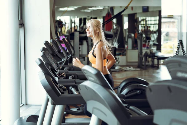 spor salonunda treadmill çalıştıran atletik sarışın kadın.
